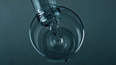 Bottle pouring pure water into transparent cup closeup. Top view liquid filling splashing glass container. Commercial shot of cool refreshing drink bubbling in jug. Wellness healthy routine concept.