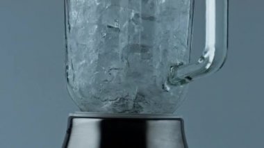 Cocktail blender grinding ice closeup. Barkeeper equipment crushing frozen cubes in container. Cool refreshing beverage preparation. Mixer machine splitting ice in cup. Making mojito drink for party