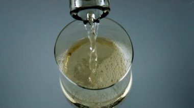 Closeup bottle pouring white wine into goblet. Fizzy drink bubbling in glass. Transparent wineglass filling with golden refreshing winery product. Fine dining celebration serving alcohol concept.