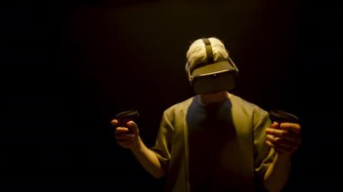 Neon gamer immersing virtual reality world in headset. Excited unknown man look controllers exploring online simulation. Blonde player enjoying metaverse technology in glasses. Futuristic game concept