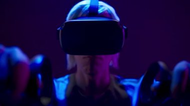 Energetic man using gaming controllers playing augmented reality simulation. VR headset youngster expressing interest engaged in futuristic metaverse world. Future innovation and technology concept