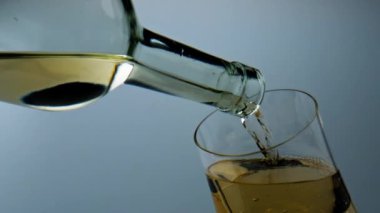 White wine filling goblet closeup. Golden grape beverage bubbling in wineglass. Single droplet falling from bottle glass. Elegant restaurant serving alcohol. Celebrating anniversary with chardonnay.