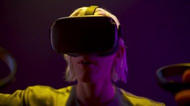 Surprised gamer playing videogame with controllers neon light. Amazed VR helmet man travelling in vr invisible world closeup. Excited guy expressing wow reaction after new augmented reality adventures
