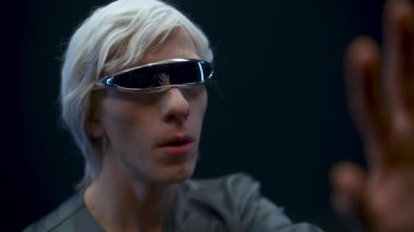 Addicted gamer examining virtual reality world closeup. Emotional shocked VR headset man immersed in 3D black background. Guy admiring augmented space playing videogame. Metaverse technology concept 
