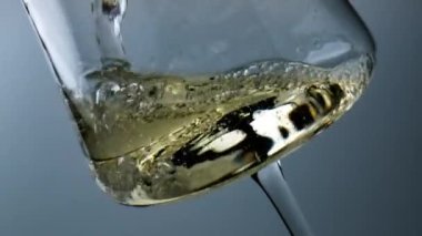 Closeup bubbling wine filling beautiful goblet. Diverse air bubbles rise liquid surface. Refreshing tasty chardonnay fizzy beverage flowing splashing in transparent glass. Party celebration concept.