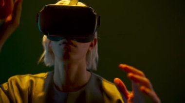 Young man touching playing virtual world game closeup. Focused gamer wearing holographic augmented reality glasses enjoying in neon light. Guy VR digital space. Metaverse 3d modern technology concept