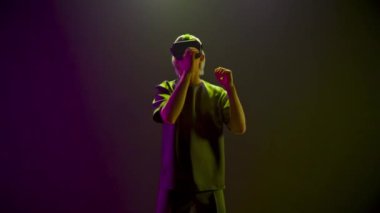 Modern man dancing in vr glasses at neon light. Blonde youngster having interaction in augmented space. Guy playing moving in cyber metaverse game. Virtual education and new reality concept 