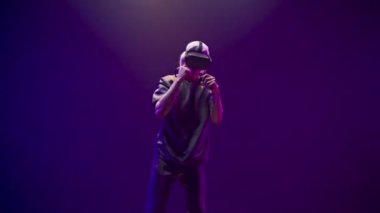 Focused teenager fighting invisible opponent in digital metaverse world. VR goggles man having fun play boxing in sport game futuristic neon colourful background. Technologies and entertainment 
