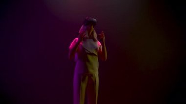 Young woman touching playing virtual world game. Amazed gamer wearing holographic augmented reality glasses enjoying in neon light. Future device girl VR space. Metaverse 3d modern technology concept