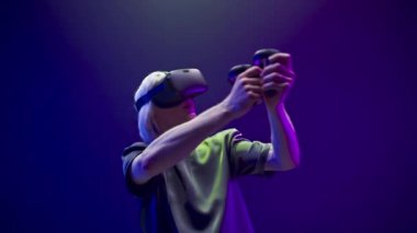Excited person enjoying VR archery video game closeup. Millennial man aiming target neon background. Active gamer playing online with controllers slow motion. Metaverse 3d modern technology concept