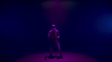 Vr man gesturing game in neon lights room. Blonde player use headset controllers in dark cyberspace. Unrecognized meta guy resting experiencing augmented reality. Trendy digital simulation concept.