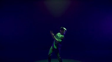 Excited player enjoying vr game in neon lights room. Futuristic man playing using headset controllers in augmented reality. Unrecognized gamer exploring metaverse simulation. Trendy innovation concept
