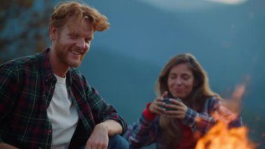 Closeup girlfriend boyfriend camping in evening mountains. Happy family relax on holiday vacation. Smiling couple enjoy hike trip by burning bonfire. Joyful lovers have fun on tourism. Active concept.