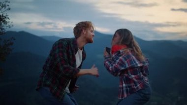 Dancing couple have fun in mountains evening. Happy lovers enjoy sunset active outdoors close up. Joyful girlfriend boyfriend move body by campfire party. Tourism holiday recreation happiness concept.