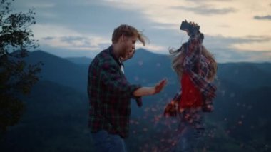 Joyful friends dance party in nature mountains landscape. Close up cheerful family enjoy fun travel on evening sunset. Happy tourists couple jump outside at dusk. Fun leisure active lifestyle concept.