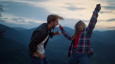 Fun family celebrate dance have fun in dusk mountains. Young couple enjoy move together outside at evening. Energetic two lovers spend time on active journey camping. Happiness leisure travel concept.