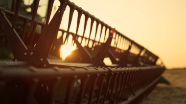Harman makinesini yaz mevsiminde Golden Sunset 'e yakın çekimde birleştirin. Harman makarası kırsal alandaki sarı arazide bulundu. Agronomik araç gökyüzü buğday arpası düştü. Yedek parça çayırı.