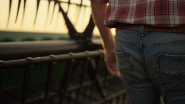 Agronomist tarla ekip biçme aracı Golden Sunset kırsalında. Çiftçinin tarla işçisi tarım yazını birleştiriyor. Çiftlik sahibi, harman makinesinin sarı görüntüsünü kontrol et. İşçi gün ışığı ufkunda yürüyor.