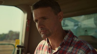 Tractor driver checking cabin before grain harvesting closeup. Focused man work in combine cockpit. Agriculture specialist examining control panel in morning farmland. Agritech professional concept.