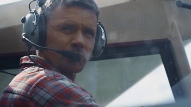 Portrait of professional aviator wearing headset in aircraft cockpit analyzing plane condition before flight. Skillful pilot man preparing to taking off sitting cabin modern airplane close up.