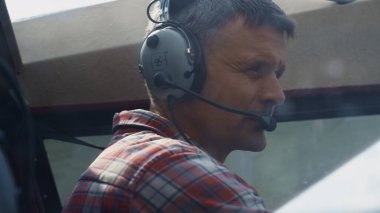Closeup airplane pilot face wearing headset with microphone sitting small plane cabin. Focused aviator making preflight checking private aircraft. Professional airman preparing air transport to flight