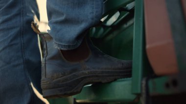 Erkek bacağı, traktör merdiveni, gün doğumunu yakından çek. Çiftçi kırsalda hasat yapmadan önce kulübeye gider. Tanınmayan sürücü tahıl tarlasında çalışıyor. Tarım uzmanı çiftlikte yeni bir çalışma gününe başladı