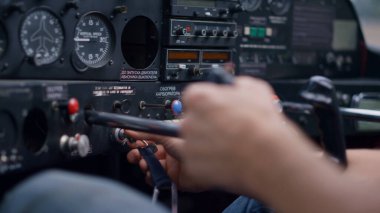 Professional pilot starting airplane engine using key sitting in modern cabin private plane closeup. Unknown aviator hands holding steering wheel in cockpit aircraft ready for flight. Aviation concept