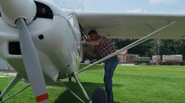 Professional pilot small airplane making preflight inspection process checking white wings. Airdrome worker inspecting private lightweight aircraft for damages before flying sky. Aviation concept.