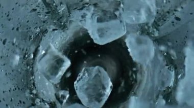 Ice cubes falling blender closeup. Grinding iced pieces in container top view. Prepare cool refreshing beverage mojito in mixer cup. Frozen chunks splitting in cup. Kitchen household equipment concept
