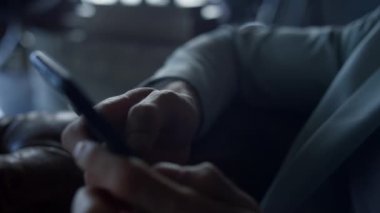 Businessman hands holding smartphone closeup. Unknown man texting business partner at dark interior hotel. Financial worker reading news going using mobile phone app. Ceo arms browsing internet 