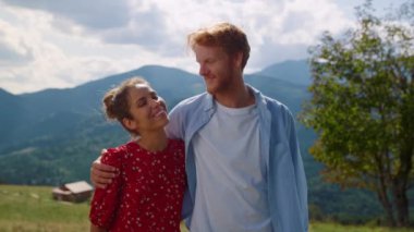 Happy couple posing in front amazing mountains looking to each other with love closeup. Cheerful man hugging pretty woman on nature sunny day. Loving pair smiling camera on summer family holiday.