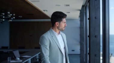 Confident businessman watching sea view. Successful pensive man ceo thinking analyzing problems and waiting in panoramic window office. Focused serious bearded professional contemplate alone
