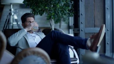 Satisfied businessman resting armchair in luxury interior. Leader person drinking whiskey and enjoying luxury hotel vacation. Thinking man tasing expensive alcohol. Confident ceo relax after work 