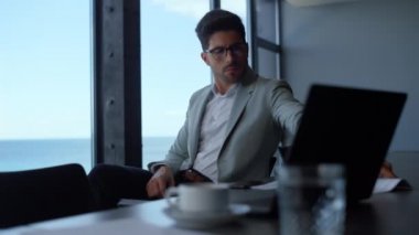 Serious businessman looking documents in luxury office. Focused entrepreneur reading papers in panorama window hotel. Handsome well groomed boss director checking financial report at sea view place 
