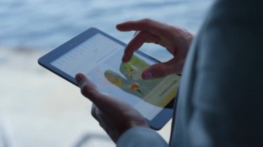 Manager hands swiping tablet screen at sea landscape place closeup. Ceo touching graph diagram and map using computer device in ocean view office. Unknown boss analyzing charts statistics at terrace 