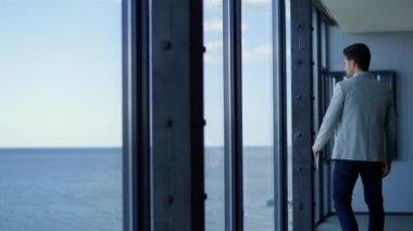 Man executive using tablet working online in ocean view office. Businessman standing panoramic window searching device. Thinking ceo professional dreaming career opportunities. Corporate concept 