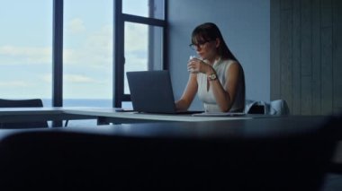 Employee holding water glass in office. Focused manager working laptop online. Brunette businesswoman hydrating searching information checking financial report. Beautiful secretary ceo look computer