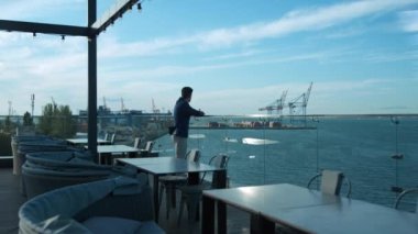 Confident man resting outdoors dreaming at sea view. Cafe owner enjoying morning on luxury terrace. Focused businessman manager relaxing on hotel rooftop. Thinking guy dreaming of life success alone