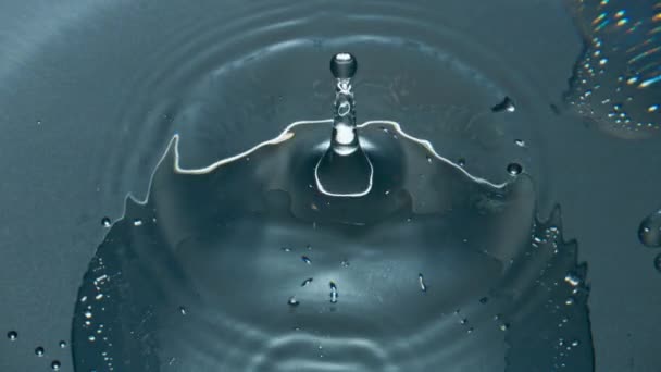 ガラス器の中で飛び散るブロブ 超スローモーションで冷たいカクテルをドロップします きれいな容器に流れる透明な液体波がマクロを確立します ろ過飲料容器表面 — ストック動画