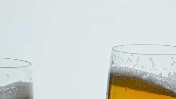 泡のビール2つのガラスの白い背景をクリックします 泡状の黄色のアルコール飲料ゴブレットがトーストを作っている 濾過されていないドラフト酔う液体クリアガラスの応援 飲料とお祝いの概念 — ストック動画