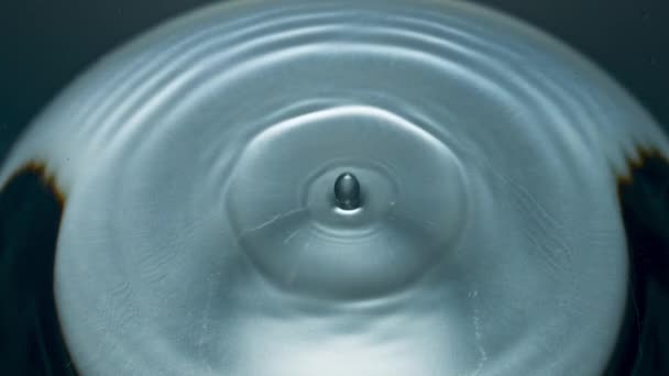 超スローモーションマクロに落ちるきれいな水のドロップ 透明なさわやかな液体ガラスを振って閉じます ろ過された飲料の塊穏やかな表面 ドリンクドリブルサークルの形状トップビューを作る 三番目の概念 — ストック動画