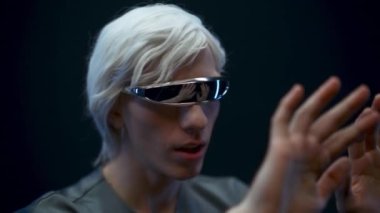 Impressed vr headset man enjoying augmented reality closeup. Astonished excited gamer amazed touching arms with open mouth black background. Guy experiencing virtual metaverse gaming first time 