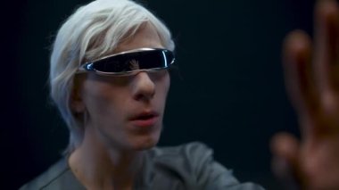 Addicted gamer examining virtual reality world closeup. Emotional shocked VR headset man immersed in 3D black background. Guy admiring augmented space playing videogame. Metaverse technology concept 