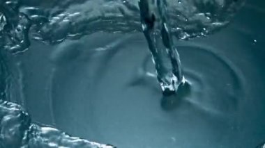 Soğuk su dökme cam üst görünümü yakın çekim. Şeffaf mineral içeceği doldurucu bardaklar süper yavaş çekimde. Beyaz arka planda filtrelenmiş su jeti dalgalanması. Yaz ferahlatıcı içecek konsepti 