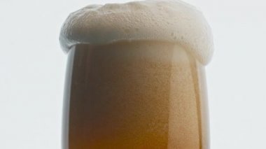 Bira bardağı köpüğü yakından taşar. Soğuk hava hafif birası süper yavaş çekimde. Zıpla, temiz içecek kap. Kenar makrodan dökülen saç köpüğü. Altın sarısı, beyaz, köpüklü alkol.