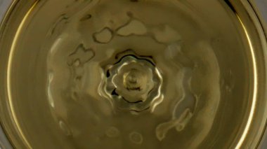 Wine drop splashing goblet closeup. Smooth liquid surface rippling waving in transparent cup. Cool chardonnay drop falling golden crystal clear liquor. Viticulture elegance dining enjoyment concept.