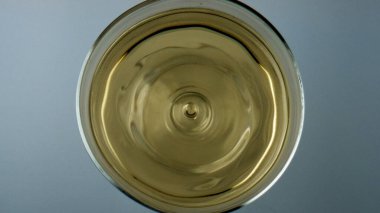 Winery droplet falling glass top view. Grape juice liquid rippling waving in cup. Golden cool sauvignon white wine beverage splashing in transparent goblet. Crystal clear beverage for celebration.