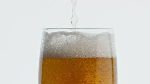 希望の液体ガラスを閉じ込めます 大麦アルコールは透明なガラス製品のマクロを飲む 濾過されていないドラフト酔う飲料ストリームは ゴブレットホワイトの背景を充填します ビールが泡立つ超スローモーション — ストック写真