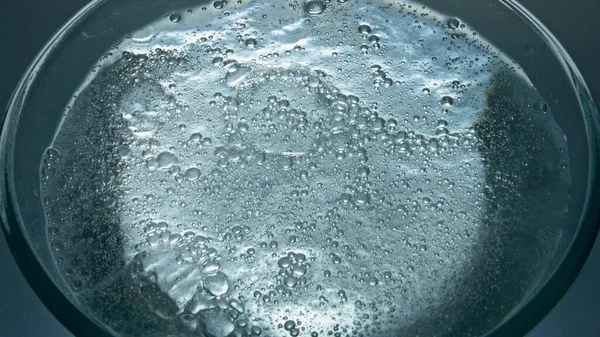 Fizzy drink bubbling inside container closeup. Water seething actively transparent vessel slow motion. Soda sparkling aqua glass macro view. Filtered liquid swashing white background. Thirst concept