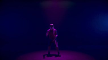 Vr man gesturing game in neon lights room. Blonde player use headset controllers in dark cyberspace. Unrecognized meta guy resting experiencing augmented reality. Trendy digital simulation concept.